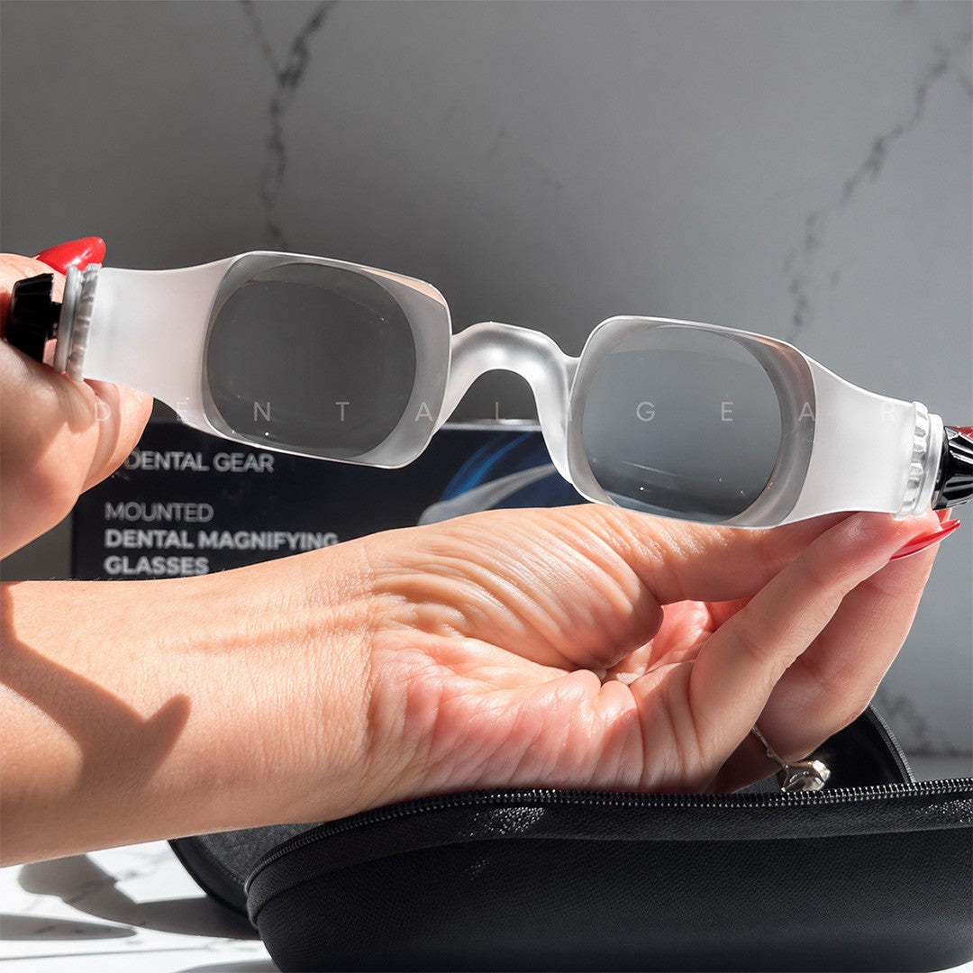Person holding dental magnifying glasses with a gray background